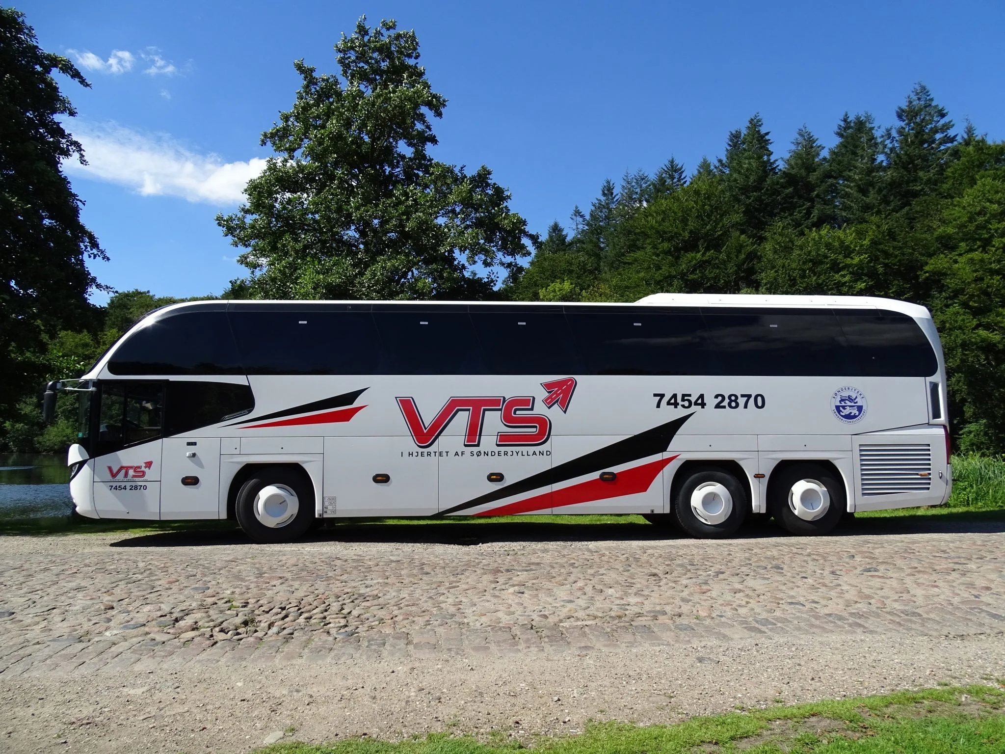 Hvid VTS-turistbus parkeret i det grønne